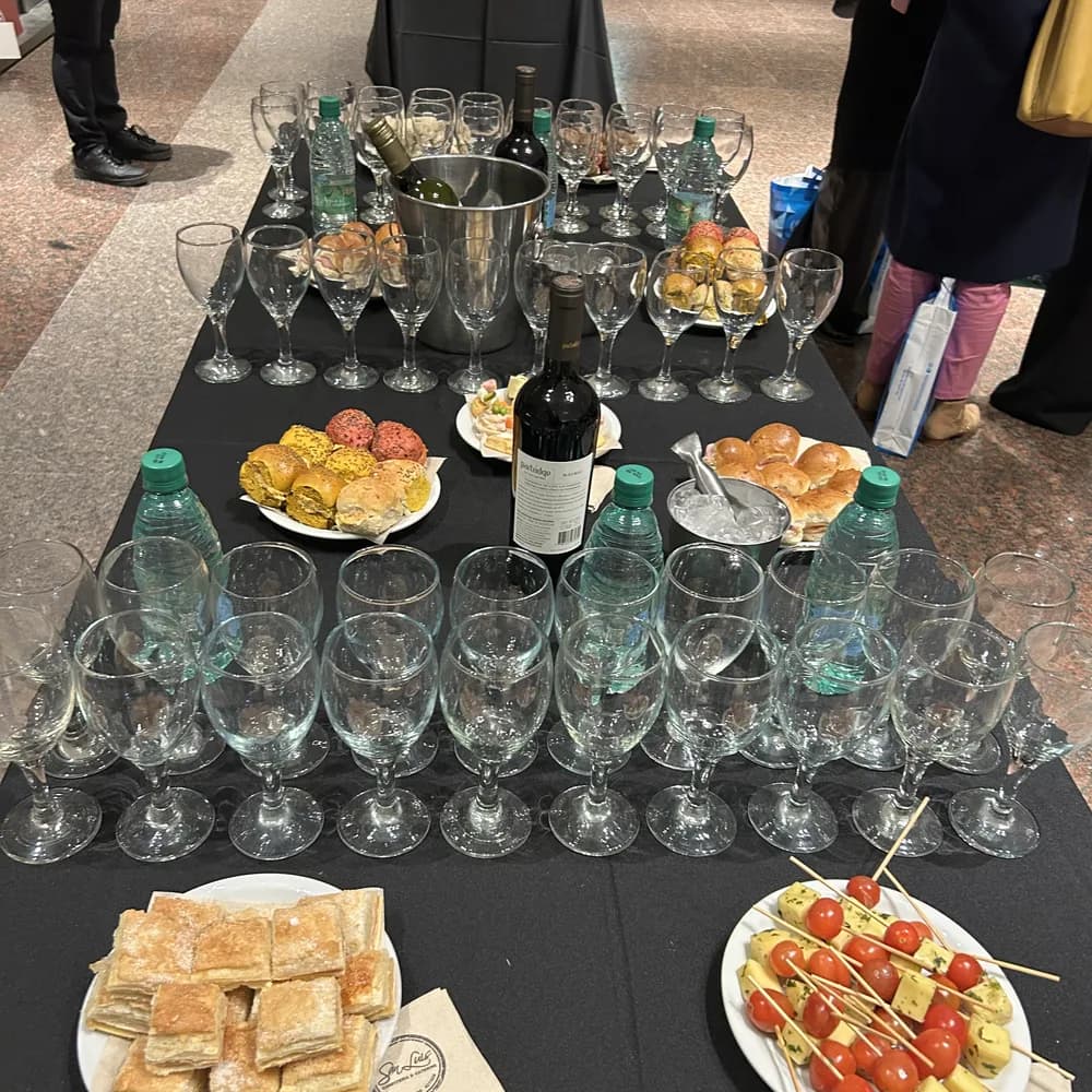 Mesa de catering armada con copas, vinos, bandejas de bocaditos y pinchos
