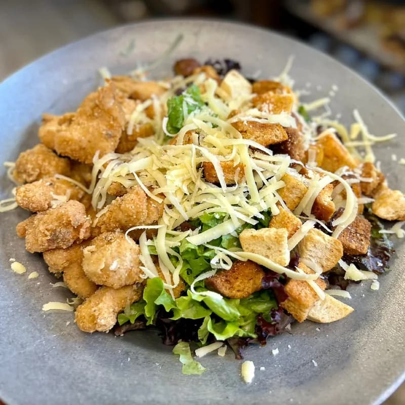 Ensalada César con pollo crocante, croutones y queso parmesano
