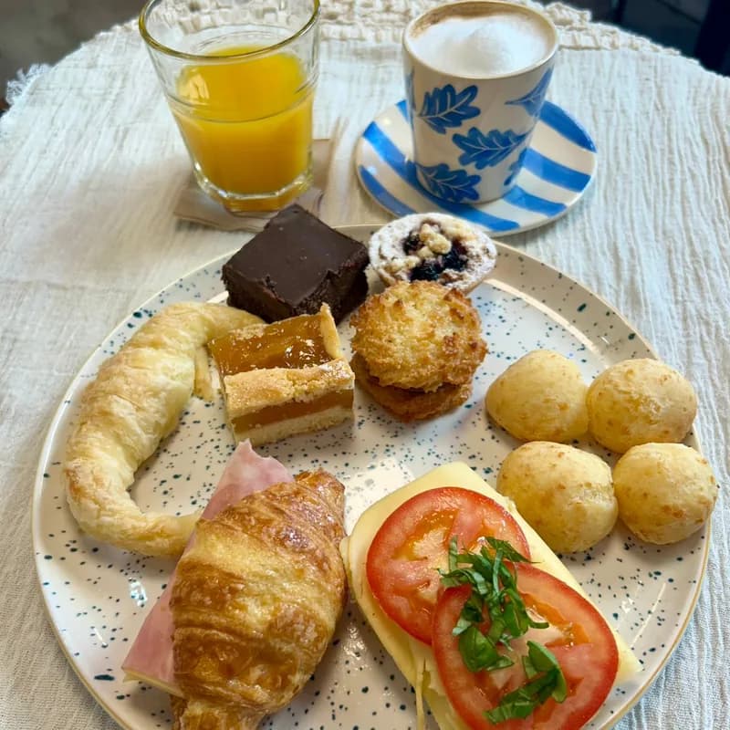 Desayuno completo de La Terraza con facturas, chipás, sándwich y café con leche