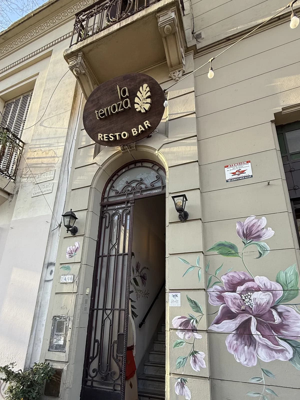 Entrada a La Terraza, restobar de Confitería San Luis en La Plata, con cartel sobre la puerta y mural floral pintado a mano